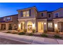 Warm home exterior at night, highlighting the cozy arched porch and landscape lighting at 3732 Via Gennaro, Henderson, NV 89044