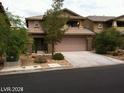 Two-story home with a two-car garage, stone accents, and manicured landscaping at 5413 Bristol Bend Ct, Las Vegas, NV 89135