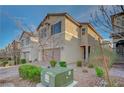 Contemporary two-story house with a two-car garage, landscaped yard, and brick driveway in a row of similar homes at 6221 Desert Orchid Way, Las Vegas, NV 89141