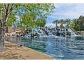 Scenic community pond featuring rock waterfall, palm trees, and lush landscaping at 1544 Karst Pond Ave, North Las Vegas, NV 89084