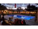 Enjoy a backyard pool under ambient lighting, complemented by cozy seating and lush greenery for tranquil evenings at 281 Deerleap Cir, Henderson, NV 89052