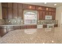 Kitchen features dark cabinets, stone countertops and mosaic tile backsplash at 9870 Giant Steps Ct, Las Vegas, NV 89141