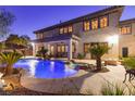 Resort-style backyard with a sparkling pool, lush greenery, rock accents, and a covered patio for outdoor dining at 10008 Peak Lookout St, Las Vegas, NV 89178