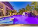 Backyard pool featuring a rock waterfall and lush landscaping, creating a private, relaxing retreat at twilight at 10008 Peak Lookout St, Las Vegas, NV 89178