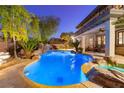 Inviting backyard oasis featuring a custom pool, rock waterfall, tropical landscaping, and a cozy seating area at 10008 Peak Lookout St, Las Vegas, NV 89178