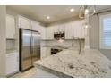 Well-lit kitchen features stainless steel appliances, granite countertops, and white cabinetry at 11396 Ogden Mills Dr # 101, Las Vegas, NV 89135