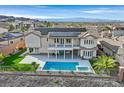 Luxury backyard with a sparkling pool, spa, covered patio, and solar panels on the roof with mountain views at 1320 Enchanted River Dr, Henderson, NV 89012