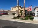 Inviting two-story home with a spacious driveway and a well-maintained front yard with lush landscaping and palm trees at 1913 April Mist St, Henderson, NV 89002