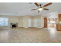 Spacious living room with tile floors, a brick fireplace, a ceiling fan, and natural light from shuttered windows at 602 Paloma Dr, Boulder City, NV 89005