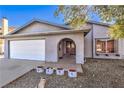 Welcoming facade showcasing a tidy front yard, an arched entryway, and a two-car garage at 6741 Bonillo Dr, Las Vegas, NV 89103