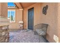Inviting front porch with decorative metal door, tiled walkway, and cozy seating area at 9076 Bridal Creek Ave, Las Vegas, NV 89178