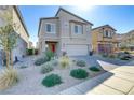 Charming two-story home boasts desert landscaping, a paver driveway, and a welcoming red front door at 10785 Wild Parsley Ave, Las Vegas, NV 89129