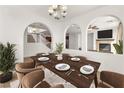 Elegant dining room featuring modern lighting, dark wood table setting, and unique arched room dividers at 2478 Cordoba Bluff Ct, Las Vegas, NV 89135