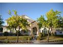 Inviting two-story home featuring a stone facade, covered entry, and lush green landscaping at 7444 Grassy Field Ct, Las Vegas, NV 89131