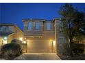 Two-story home with a two car garage, desert landscaping and exterior lighting at dusk at 8558 Rumsfield Ct, Las Vegas, NV 89131