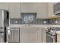 Kitchen with stainless steel appliances, stylish backsplash, light gray cabinets, and white quartz countertops at 1103 Tektite Ave, Henderson, NV 89011