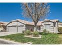 Single-story home with three car garage, desert landscaping and bright green lawn at 1110 Legato Dr, Las Vegas, NV 89123