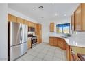 Bright kitchen with stainless steel appliances, wood cabinets, white tile backsplash, and tile flooring throughout at 2201 Tiger Links Dr, Henderson, NV 89012