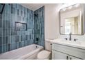 Stylish bathroom boasting blue tiled walls, a tub, modern fixtures, and a contemporary vanity with a rectangular mirror at 4954 Palmyra Ave, Las Vegas, NV 89146