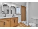 Bright bathroom featuring double sinks, modern mirrors, wood vanity and a glass-enclosed shower at 528 Sheffield Dr, Henderson, NV 89014