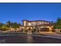 Stunning home with a stone turret, tile roof, arched windows, and professional landscaping at twilight at 6 Fire Rock Ct, Las Vegas, NV 89141