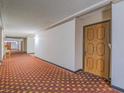 The condominium hallway with patterned carpet leads to the front door of a unit at 725 N Royal Crest Cir # 213, Las Vegas, NV 89169