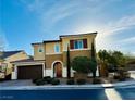 Two story tan home with tile roof, front yard with landscaping at 945 Pomander Point Pl, Henderson, NV 89012