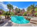 Backyard pool with lush tropical landscaping, rock accents, and lounge seating, ideal for relaxation at 5868 Revital Ct, Las Vegas, NV 89131