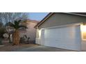 This house features a two car garage with neutral paint, a red roof, and some small landscaping at 5875 Rainbow Bridge Dr, Las Vegas, NV 89142