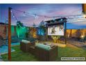 Outdoor entertainment area featuring comfortable seating, a large screen TV, and stylish string lights at 9091 Becket Ranch Ct, Las Vegas, NV 89113