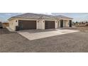 This home features a three-car garage, gray roof, minimalist front yard, and tasteful dark trim at 1601 W Calvada Blvd, Pahrump, NV 89048