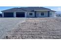 Single-story home with a gray roof, three-car garage, and minimalist front yard in a desert community at 1601 W Calvada Blvd, Pahrump, NV 89048
