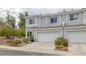 Desirable townhome features light gray exterior, a two-car garage, and charming landscaping for attractive curb appeal at 2405 Esteem Ridge Dr, Henderson, NV 89052