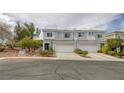 Beautiful townhome showcasing light gray stucco, a two-car garage, and tasteful landscaping for enhanced curb appeal at 2405 Esteem Ridge Dr, Henderson, NV 89052