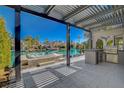 Beautiful waterfront outdoor patio featuring a hot tub, built-in grill, and shaded pergola with waterfront view at 3012 Waterside Cir, Las Vegas, NV 89117