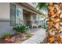A welcoming front porch featuring a stone walkway, charming white benches, and lush potted plants at 404 Via Sonador, Henderson, NV 89012