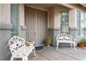 Inviting front porch with decorative white benches, elegant potted plants, and a charming double-door entrance at 404 Via Sonador, Henderson, NV 89012