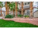 Charming home with lush lawn, mature palm trees, and a brick retaining wall showcasing curb appeal at 404 Via Sonador, Henderson, NV 89012
