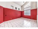Spacious living room with tile flooring, a large window, and a contrasting red accent wall at 7267 Sequoia Springs Dr, Las Vegas, NV 89147