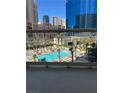 Balcony view of a sunny outdoor pool area with lounge chairs and palm trees, surrounded by city buildings at 135 E Harmon Ave # 307, Las Vegas, NV 89109