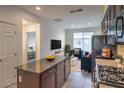 Open-concept kitchen featuring modern appliances, dark wood cabinetry, and an island bar area for casual dining at 4542 Townwall St, Las Vegas, NV 89115