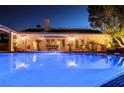 Night view of a private backyard pool reflecting the house lights in the clear, blue water at 692 Quilt Pl, Henderson, NV 89052