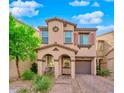 Charming two-story home with a covered entry, arched columns, tan stucco, and a lush landscaped yard and brick paver driveway at 8349 Spruce Bay Ave, Las Vegas, NV 89178