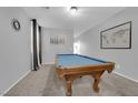 Spacious game room featuring a blue felt pool table, neutral carpet, gray walls, and bright natural light at 8349 Spruce Bay Ave, Las Vegas, NV 89178