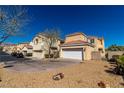 Tan two-story home featuring a two car garage and low maintenance desert landscaping at 1016 Douglas Flat Pl, Las Vegas, NV 89138