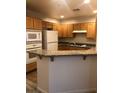 A well-lit kitchen featuring granite counters, wood cabinets and a breakfast bar at 19 E Agate Ave # 406, Las Vegas, NV 89123