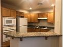 Bright kitchen with granite countertops, wooden cabinets and white appliances at 19 E Agate Ave # 406, Las Vegas, NV 89123