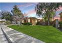 Well-maintained front yard with mature trees and green lawn, complementing the house's exterior at 2213 Midvale Ter, Henderson, NV 89074