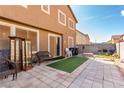 A backyard patio boasts stone pavers, furniture, and artificial turf, ideal for outdoor entertaining and relaxation at 1930 Silver Crest Ct, North Las Vegas, NV 89031