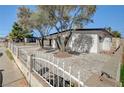 Well-maintained home with white picket fence, mature trees, and low-maintenance gravel landscaping at 2512 Taylor Ave, North Las Vegas, NV 89030